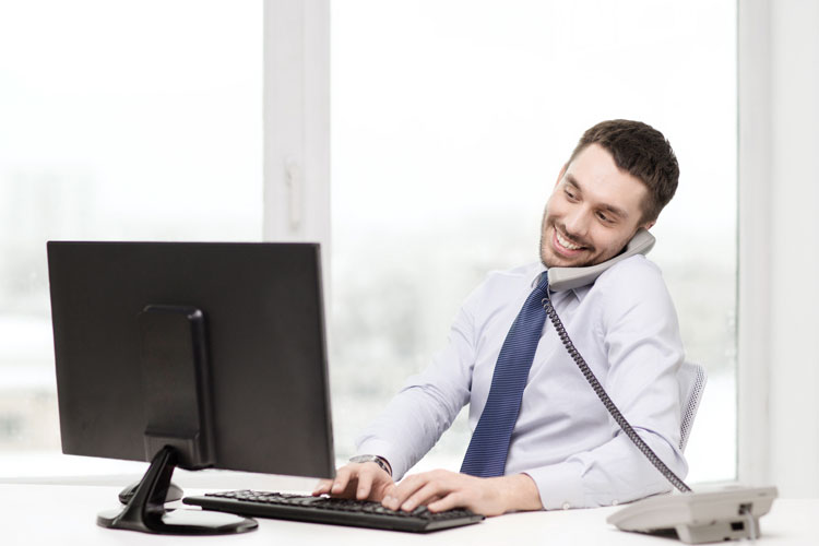 picture-of-a-smiling-man-on-telephone-typing-on-computer